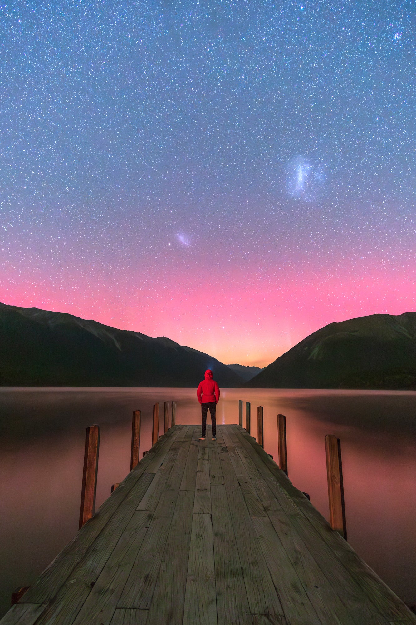 Man standing at the edge of dock looking at the aurora australis