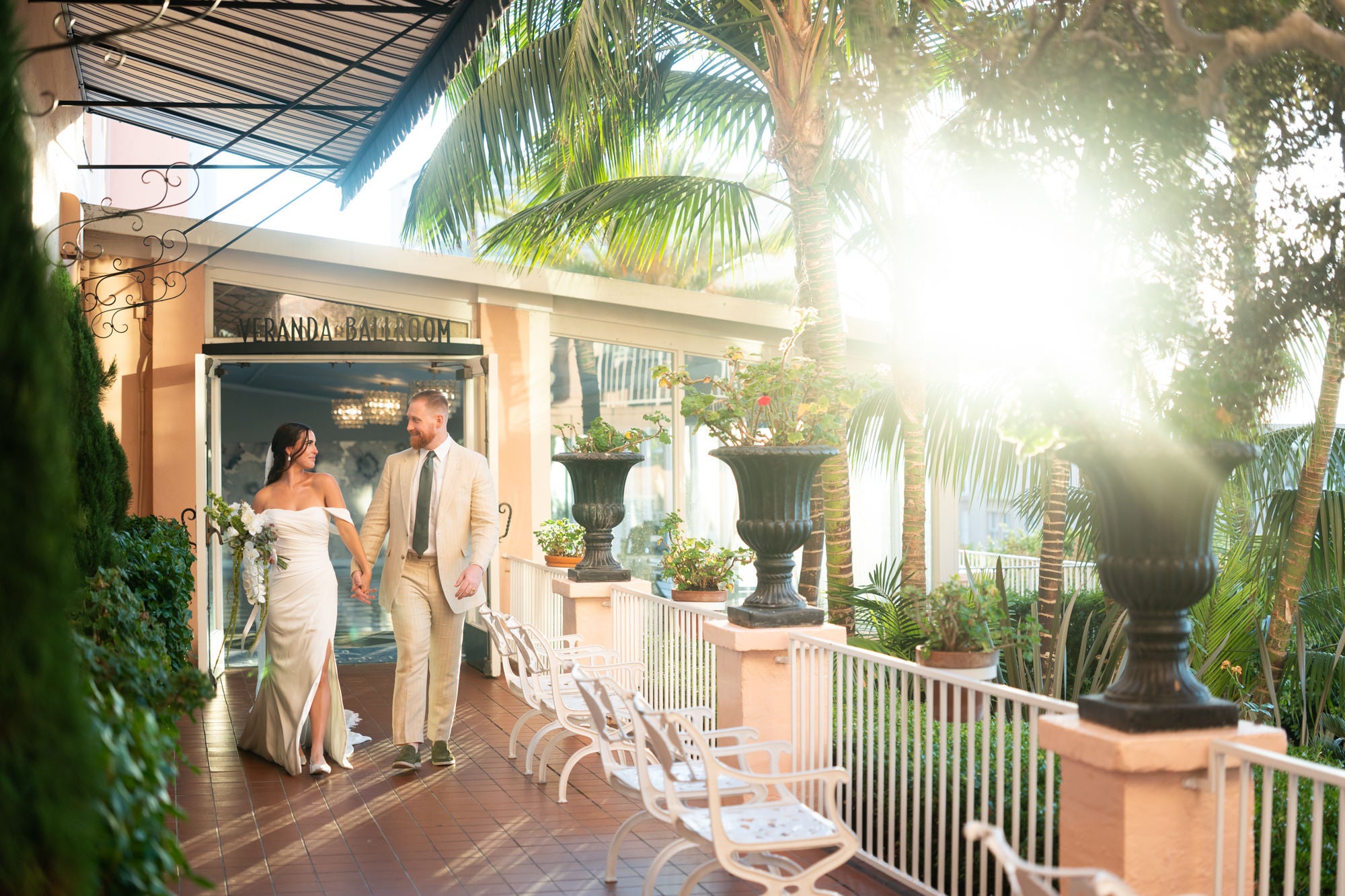Bride and groom walking together across outdoor ballroom deck at sunset