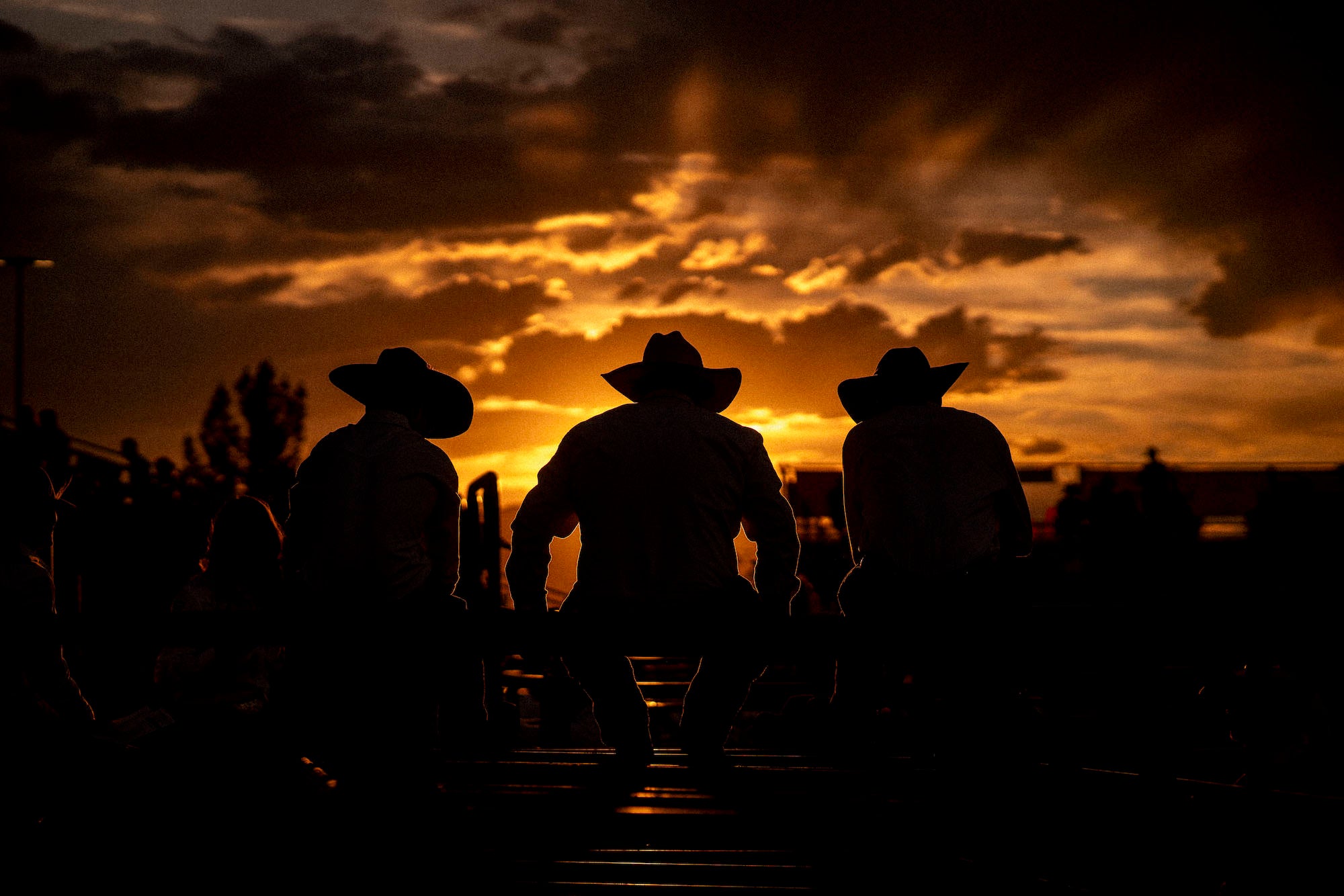 Silhouette photo of cowboys sitting together at sunset