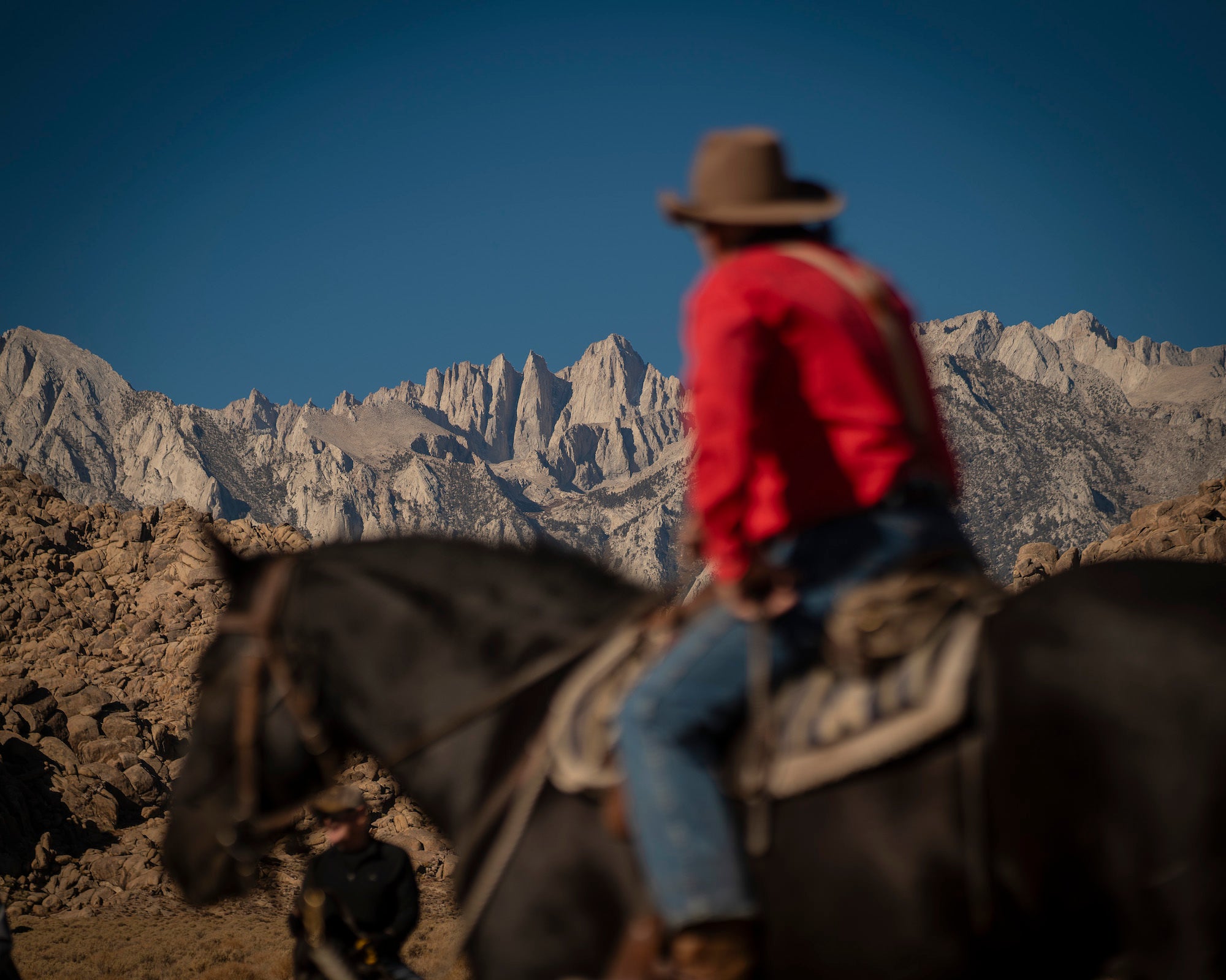 Cowboy on top of horse with mountains in the background