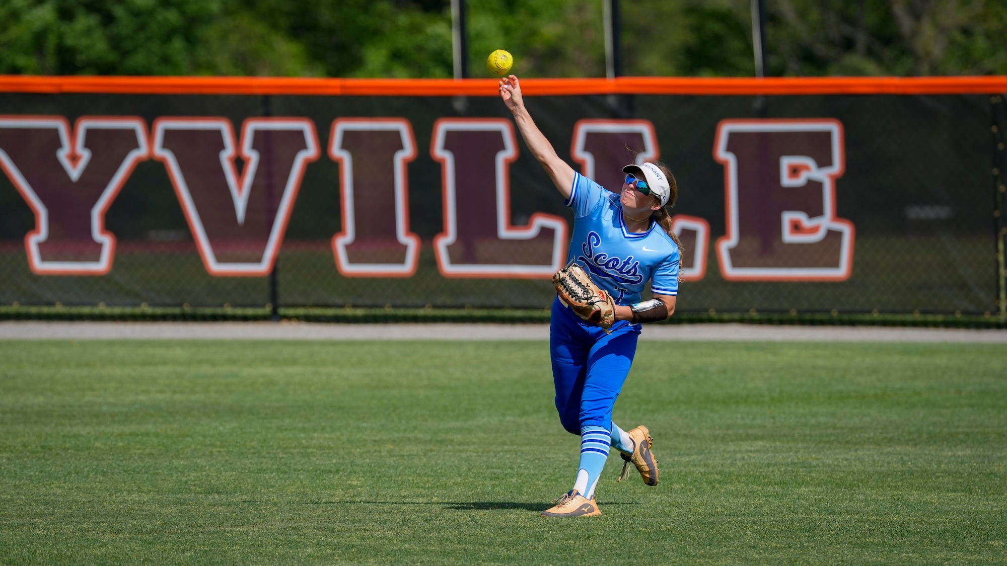 Softball player in the outfield throwing in the ball.