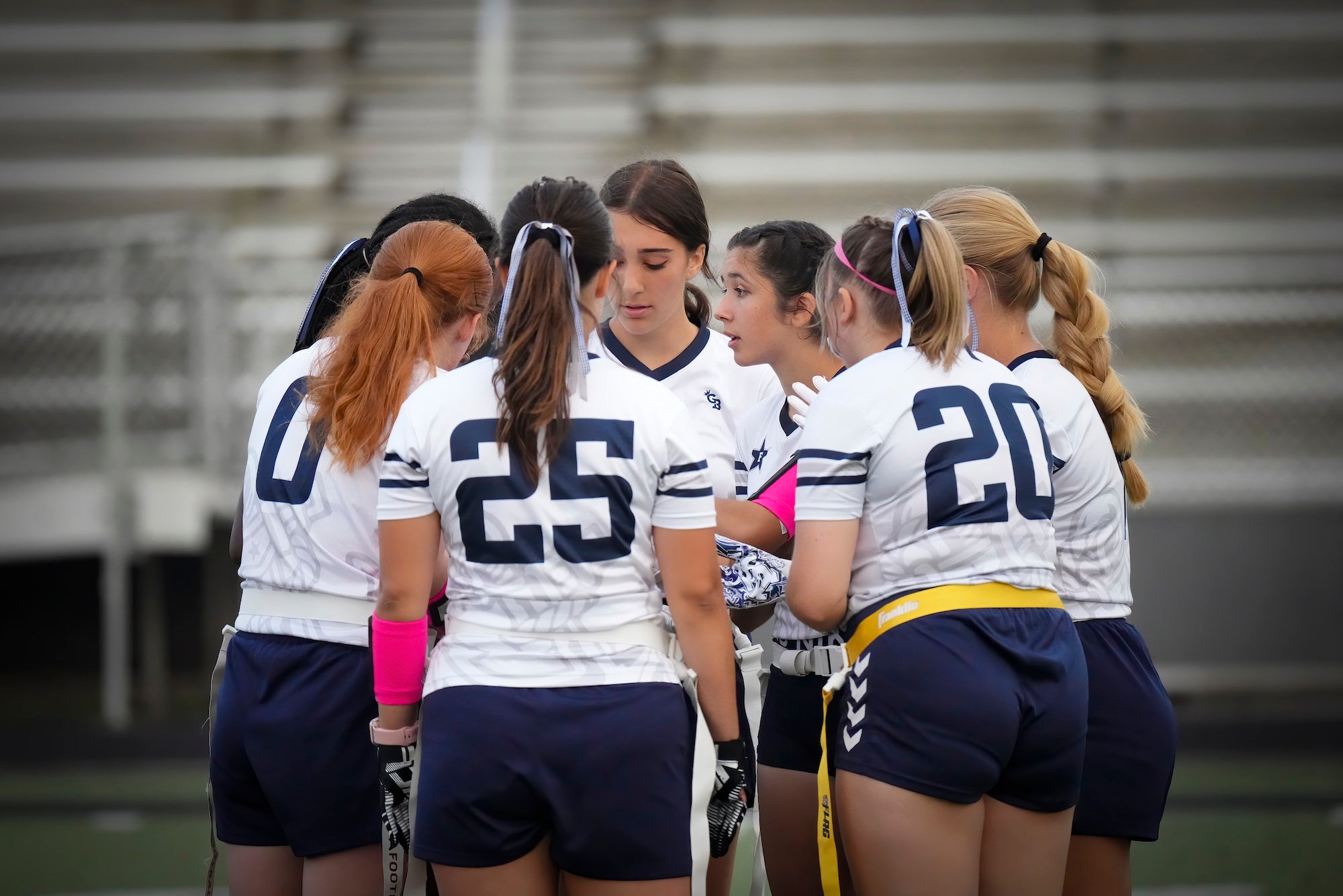 Girls flag football team in a huddle.