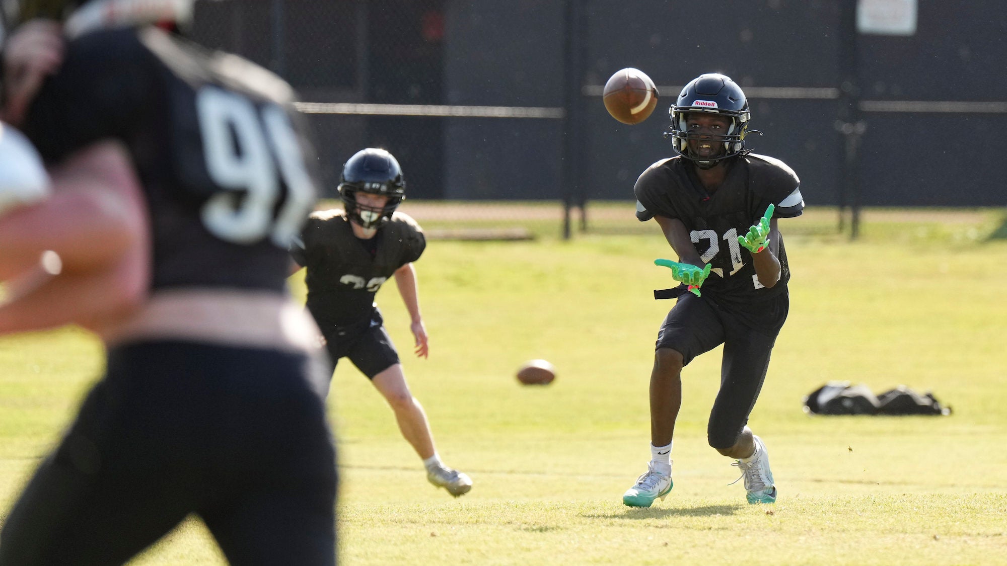 Football player in black jersey catches a football.