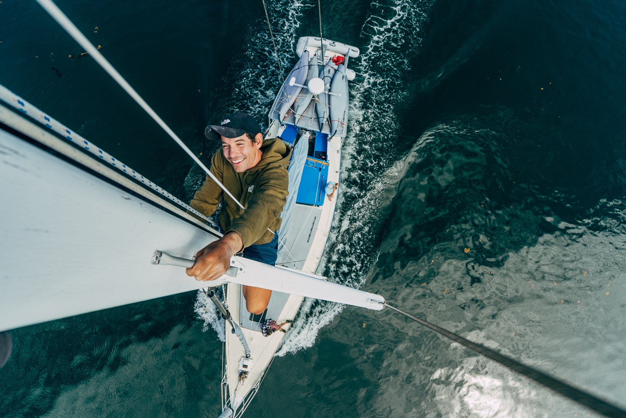 A photo from above of Alex Honnold climbing the mast of a sailboat.
