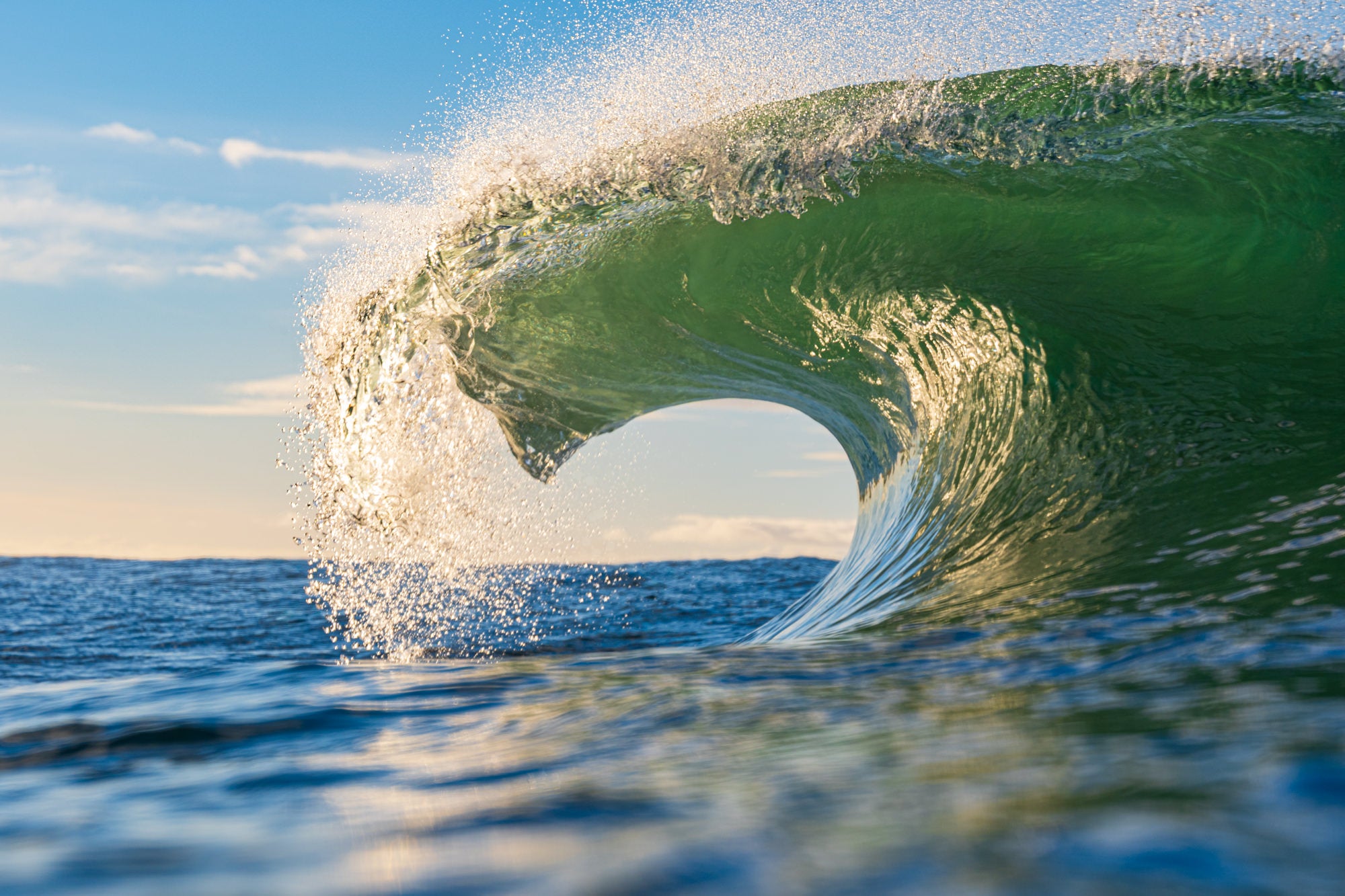 A wave cresting in the ocean during the day