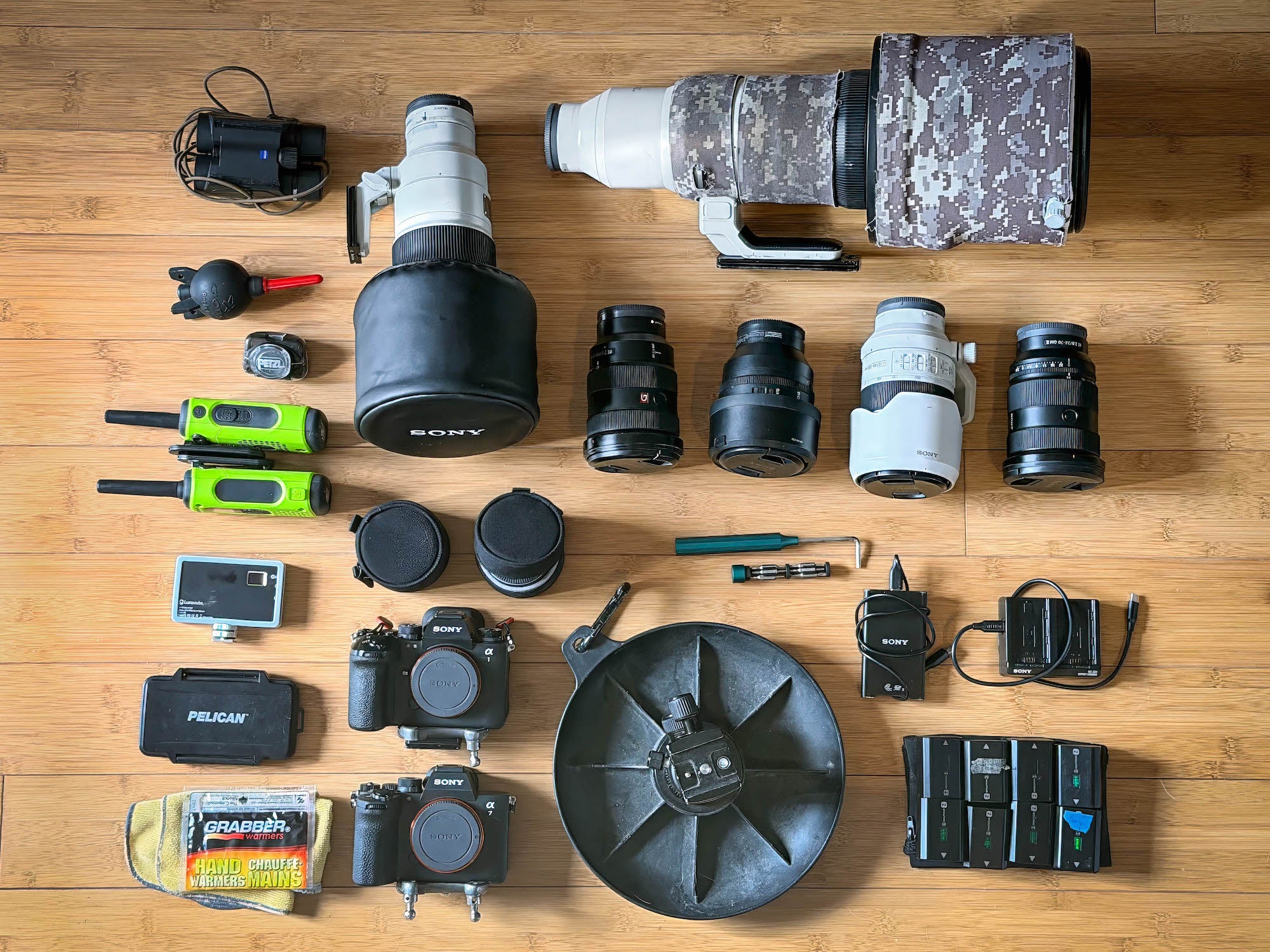 Flat lay of wildlife photo gear—cameras, long lenses, radios, batteries—on wood floor. Flat lay of wildlife photo gear—cameras, long lenses, radios, batteries—on wood floor.