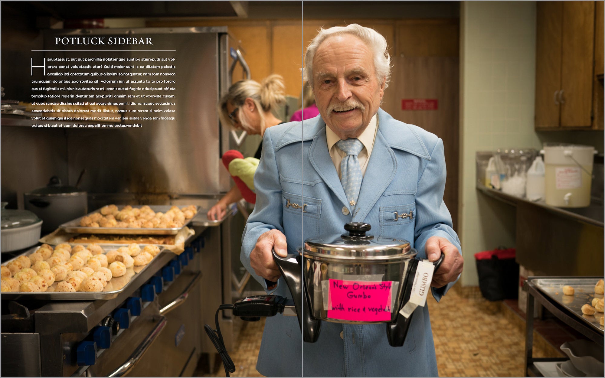 Man in a kitchen holds a pot labeled &ldquo;gumbo&rdquo; while trays of rolls bake and another cook works behind him.