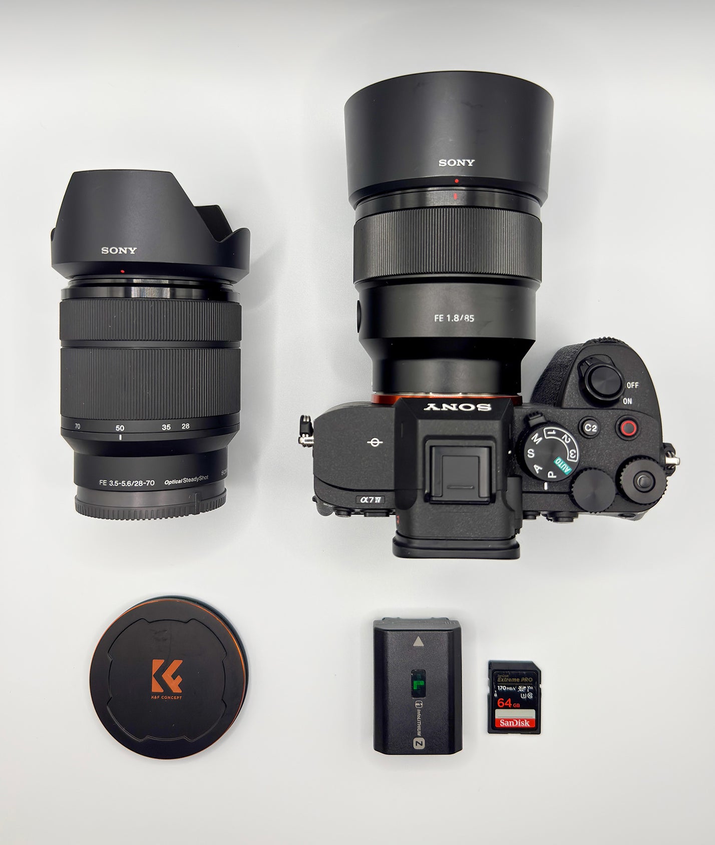 Sony Alpha camera with 85mm, 28&ndash;70mm lens, battery and SD cards arranged for a what&rsquo;s in my bag feature.
